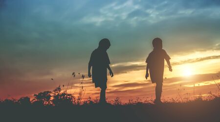 Silhouette, group of happy children playing on meadow, sunset, summertimeの写真素材