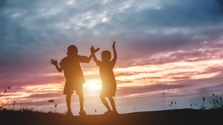 Silhouette, group of happy children playing on meadow, sunset, summertimeの写真素材