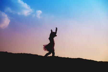 Silhouette of girl praying over beautiful sky backgroundの写真素材