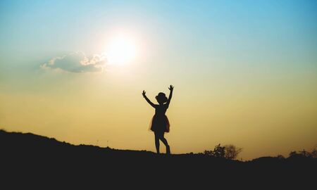 Silhouette of girl praying over beautiful sky backgroundの写真素材