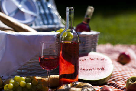 Wine and picnic basket on the grass の写真素材