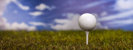 Golf ball on green grass over a blue sky の写真素材