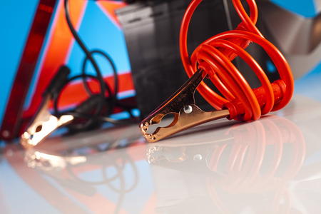 Car battery with two jumper cables clipped on vivid moto conceptの写真素材