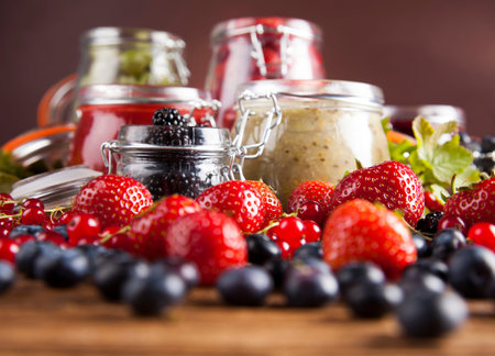 Jams in glass jars with wood and fresh berriesの写真素材
