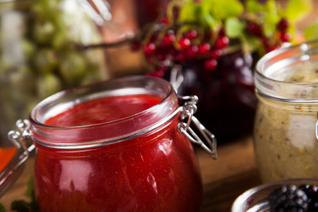 Jams in glass jars with wood and fresh berriesの写真素材