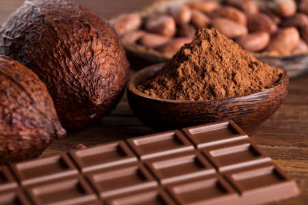 Chocolate bar, candy sweet, cacao beans and powder on wooden backgroundの写真素材