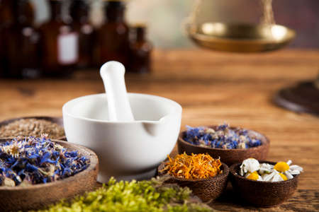 Herbs, berries and flowers with mortar, on wooden table backgroundの写真素材