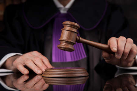 Judge, male judge in a courtroom striking the gavelの写真素材