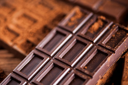 Chocolate bar, candy sweet, cacao beans and powder on wooden background