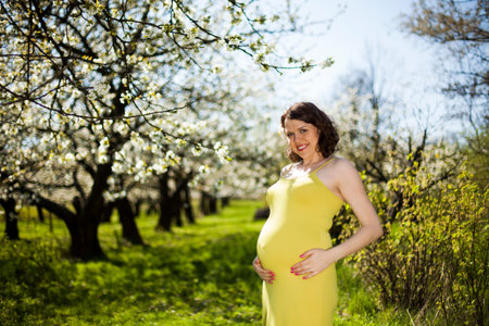 Beautiful pregnant woman relaxing outside in the Orchard