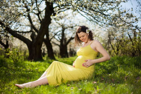 Beautiful pregnant woman relaxing outside in the Orchardの写真素材