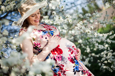 Beautiful pregnant woman relaxing outside in the Orchardの写真素材