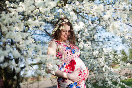 Beautiful pregnant woman relaxing outside in the Orchardの写真素材