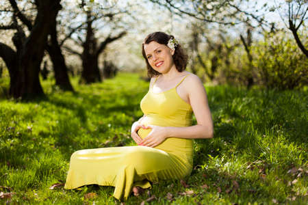 Beautiful pregnant woman relaxing outside in the Orchardの写真素材