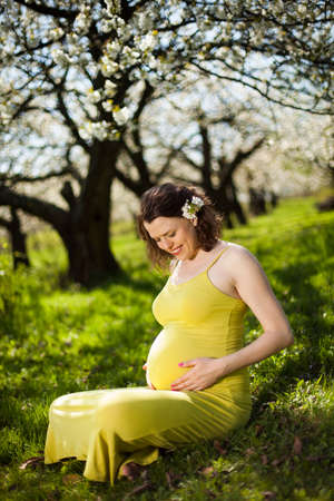 Beautiful pregnant woman relaxing outside in the Orchardの写真素材