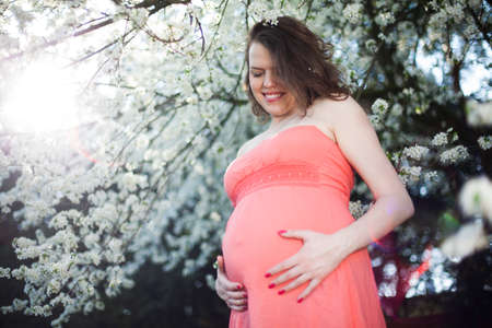 Beautiful pregnant woman relaxing outside in the Orchardの写真素材