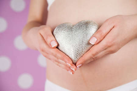 Pregnant woman holding a heartの写真素材
