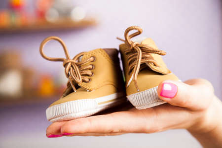 Pregnant woman holding baby shoes in her handsの写真素材