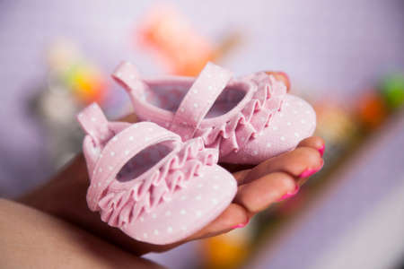 Pregnant woman holding baby shoes in her handsの写真素材