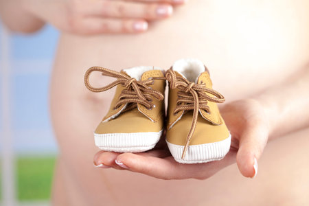 Pregnant woman holding baby shoes in her handsの写真素材