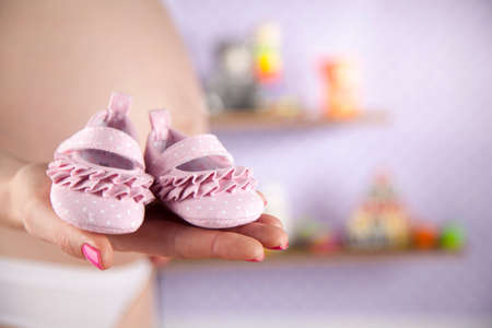 Pregnant woman holding baby shoes in her handsの写真素材