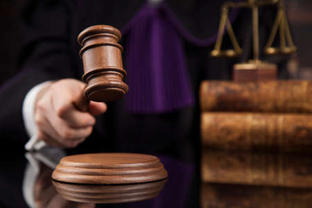 male judge in a courtroom striking the gavelの写真素材