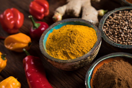 A selection of various colorful spices on a wooden table in bowls