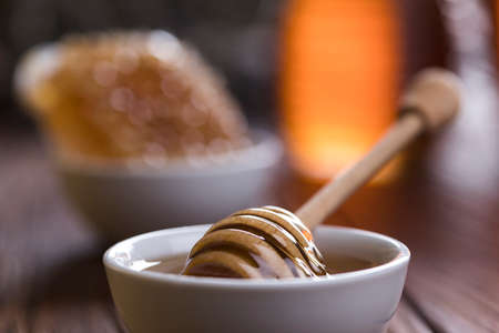 Honey in the comb, glass jar on wooden backgroundの写真素材