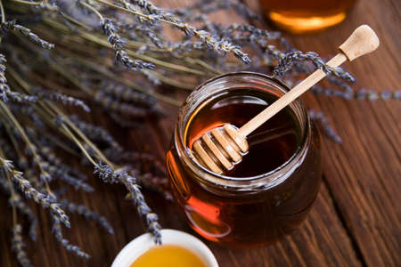 Honey in jar with honey dipper on wooden backgroundの写真素材