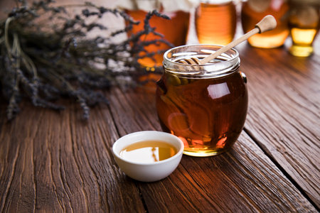 Honey in jar with honey dipper on wooden backgroundの写真素材