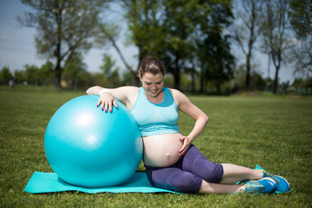 Beautiful young pregnant woman exercises with  fitball in the gymの写真素材