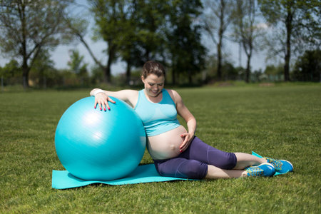 Beautiful young pregnant woman exercises with fitball in the gymの写真素材
