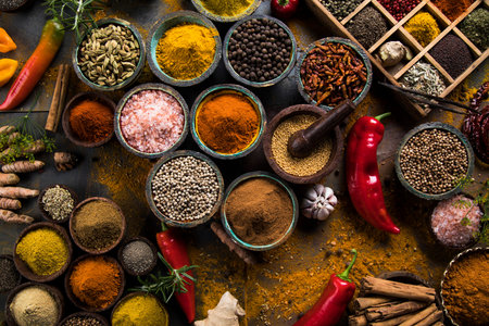 A selection of various colorful spices on a wooden table in bowlsの写真素材