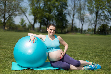 Beautiful young pregnant woman exercises with fitball in the gymの写真素材