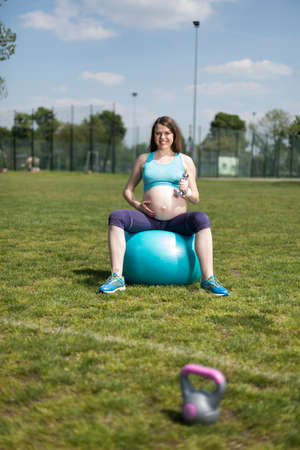 Beautiful young pregnant woman exercises with fitball in the gymの写真素材