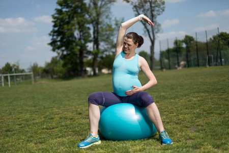Beautiful young pregnant woman exercises with fitball in the gymの写真素材