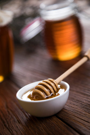 Honey in jar with honey dipper on wooden background