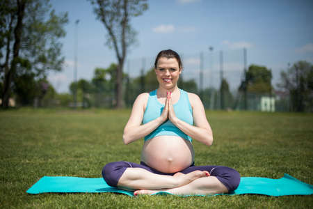 Healthy pregnant woman doing yoga in natureの写真素材