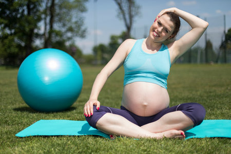 Healthy pregnant woman doing yoga in natureの写真素材