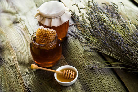 Honey in jar with honey dipper on wooden backgroundの写真素材