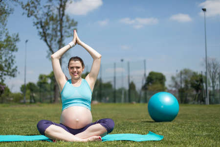Pregnant woman doing yoga in natureの写真素材
