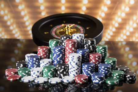 Poker Chips on gaming table, roulette wheel in motion, casino backgroundの写真素材