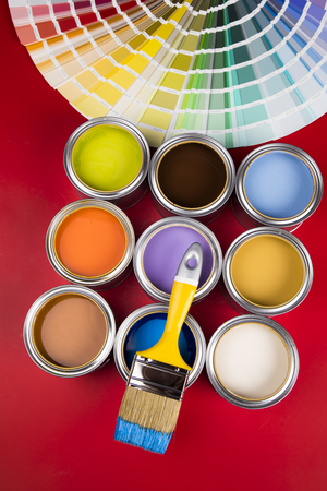 Buckets full of rainbow colored oil paint, red backgroundの写真素材