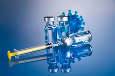 Vaccine vials and syringe on blue background with reflectionの写真素材
