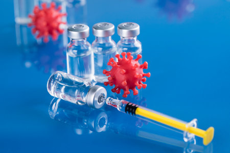 Vaccine and syringe with coronavirus on blue backgroundの写真素材