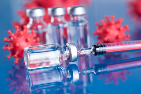 Vaccine vials and syringe on blue reflective surface.の写真素材