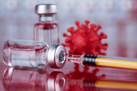 Vaccine vials and syringe on a reflective surface.の写真素材