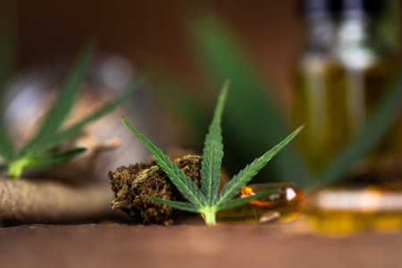 Cannabis oil in a glass bottle with marijuana leaves on wooden backgroundの写真素材