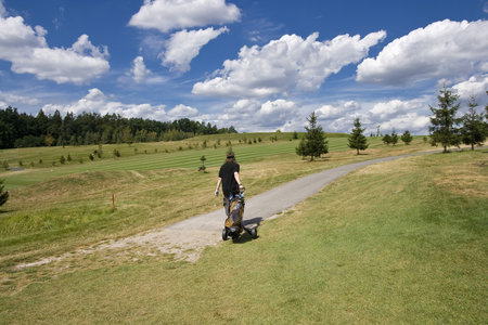 fairway of a beautiful golf course with golfer under dramatic summer skyの写真素材