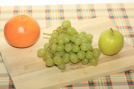 Fresh green grapes, apple and grapefruit on a tableの写真素材